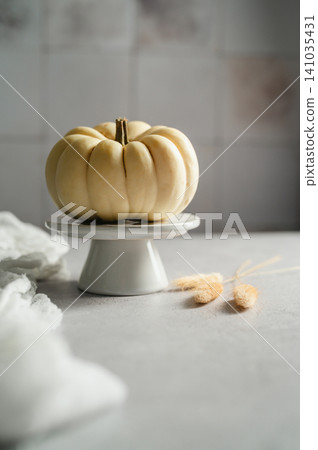 White ornamental pumpkin on cake stand, minimalist autumn still life White ornamental pumpkin on cake stand, minimalist autumn still life 141035431