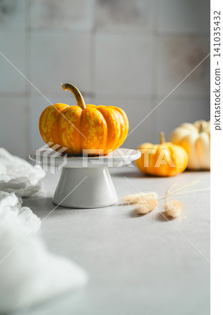 Ornamental pumpkin on white cake stand, cozy autumn still life, copy space Ornamental pumpkin on white cake stand, cozy autumn still life, copy space 141035432