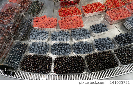Fresh assortment of cherries, raspberries, blueberries and red currants displayed in plastic containers at a local farmers market with vibrant summer colors. Fresh assortment of cherries, raspberries, blueberries and red currants displayed in plastic containers at a local farmers market with vibrant summer colors. 141035731