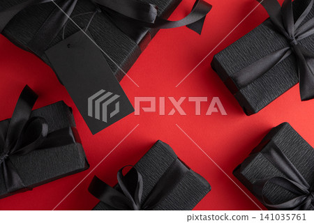 Black gift boxes with blank tag on red background Black gift boxes with blank tag on red background 141035761