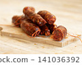 Sliced Spanish Chorizo Sausages on Wooden Cutting Board 141036392