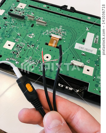 Hand using black pliers to work on a green circuit board of a disassembled car radio. Hand using black pliers to work on a green circuit board of a disassembled car radio. 141036718