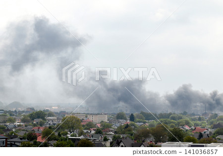 Thick black smoke rising over residential area after explosion or missile strike in Ukraine. Urban skyline under attack, air raid damage, war conflict or fire emergency concept Thick black smoke rising over residential area after explosion or missile strike in Ukraine. Urban skyline under attack, air raid damage, war conflict or fire emergency concept 141036857