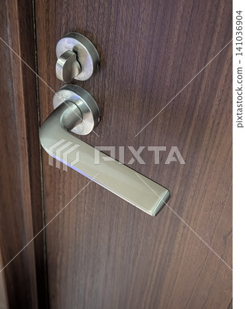 Close-up of the silver door handle and lock attached to the wooden door. 141036904