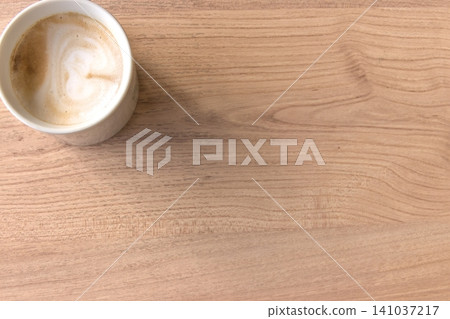 A warm latte placed on a wooden table, overhead view, copy space, background material, landscape orientation. A warm latte placed on a wooden table, overhead view, copy space, background material, landscape orientation. 141037217