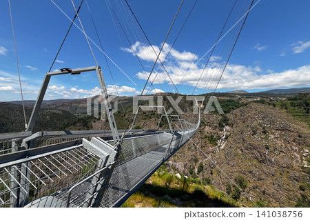Arouca 516 suspension bridge crossing a dramatic valley in Portugal, showcasing modern engineering, adventure tourism, geometric design, scenic landscapes, and outdoor exploration Arouca 516 suspension bridge crossing a dramatic valley in Portugal, showcasing modern engineering, adventure tourism, geometric design, scenic landscapes, and outdoor exploration 141038756