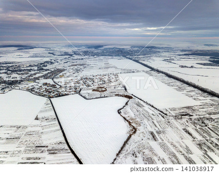 Top view of empty snowy fields on winter morning on dramatic cloudy sky background. Aerial drone photography concept. Top view of empty snowy fields on winter morning on dramatic cloudy sky background. Aerial drone photography concept. 141038917