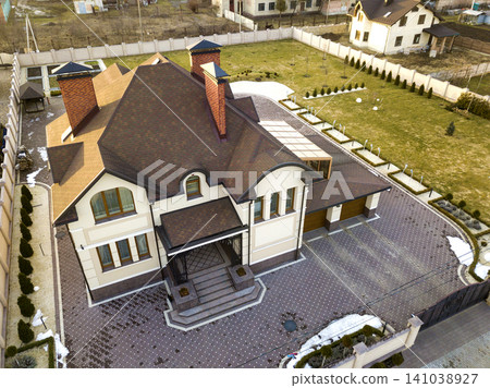 Aerial top view of new residential house cottage with shingle roof on fenced big yard on sunny day. Aerial top view of new residential house cottage with shingle roof on fenced big yard on sunny day. 141038927