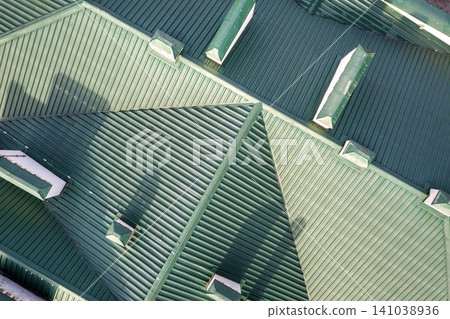 Top aerial view of building green shingle tiled roof with complex configuration construction. Abstract background, geometrical pattern. Top aerial view of building green shingle tiled roof with complex configuration construction. Abstract background, geometrical pattern. 141038936