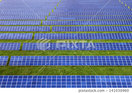 Large field of solar photo voltaic panels system producing renewable clean energy on green grass background. 141038960