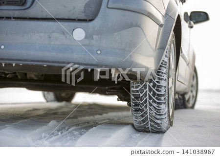 Close up of a car tire parked on snowy road on winter day. Transportation and safety concept. Close up of a car tire parked on snowy road on winter day. Transportation and safety concept. 141038967