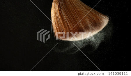 Big Soft Makeup brush with powder explosion. Cosmetic brush splash powder dust with glitter sparkling for make up. Black background isolated on photo element Big Soft Makeup brush with powder explosion. Cosmetic brush splash powder dust with glitter sparkling for make up. Black background isolated on photo element 141039111