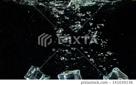 Falling ice cube pieces with water splashing in midair on a transparent, isolated black background. Ice cubes drop into water with air bubbles scatter splashing Falling ice cube pieces with water splashing in midair on a transparent, isolated black background. Ice cubes drop into water with air bubbles scatter splashing 141039136