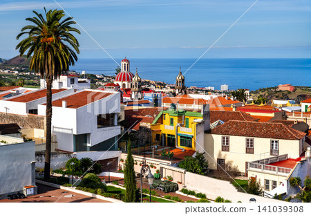 Panoramic view over the historic town of La Orotava featuring the Church of Our Lady of Conception and red tiled roofs with the Atlantic Ocean in the distance, Tenerife, Spain Panoramic view over the historic town of La Orotava featuring the Church of Our Lady of Conception and red tiled roofs with the Atlantic Ocean in the distance, Tenerife, Spain 141039308