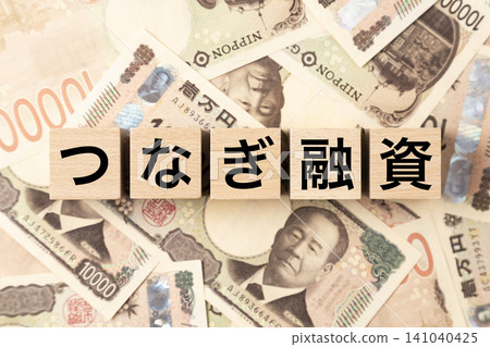 一塊寫著「過橋貸款」字樣的磚塊和許多10,000日圓面額的鈔票。 141040425