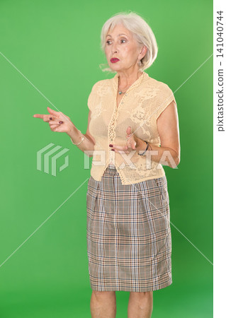 Mature woman in summer clothes looks and looks around on green background Mature woman in summer clothes looks and looks around on green background 141040744