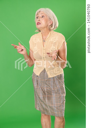 European senior woman in beige suit on green screen background speaks or addresses imaginary partner European senior woman in beige suit on green screen background speaks or addresses imaginary partner 141040760