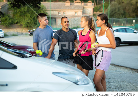 Positive tennis players talking on parking lot Positive tennis players talking on parking lot 141040799