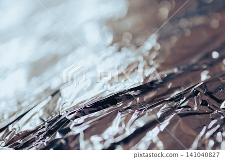 Abstract silver metal foil background with a crumpled surface and reflecting light, creating shiny textures and artistic bokeh effects for design Abstract silver metal foil background with a crumpled surface and reflecting light, creating shiny textures and artistic bokeh effects for design 141040827