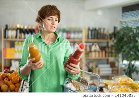 Adult woman chooses peach and tomato juices Adult woman chooses peach and tomato juices 141040853