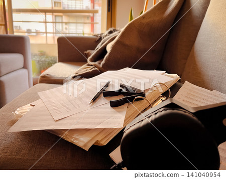 Home study setup for creating or learning music, featuring an acoustic guitar, sheet music, pen and a capo, representing creativity, education, and artistic expression Home study setup for creating or learning music, featuring an acoustic guitar, sheet music, pen and a capo, representing creativity, education, and artistic expression 141040954