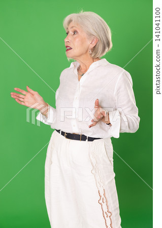 Elderly woman looking around in front of green screen Elderly woman looking around in front of green screen 141041100