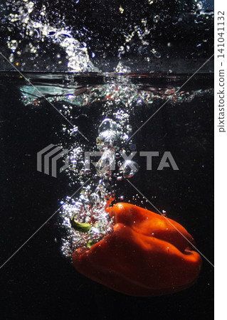 Red bell pepper splashing into fresh clear water creating bubbles 141041132