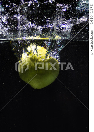 Green fruit splashing into clean fresh water creating bubbles Green fruit splashing into clean fresh water creating bubbles 141041178