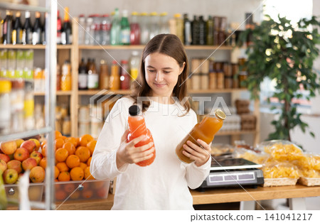 Teenage girl chooses grapefruit and peach juices Teenage girl chooses grapefruit and peach juices 141041217