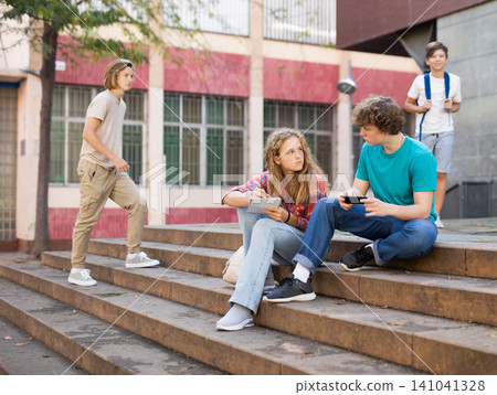 Boy and girl teens sitting on stairs and doing homework Boy and girl teens sitting on stairs and doing homework 141041328
