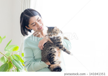 一位女士抱著她的寵物貓。 一位女士抱著她的寵物貓。 141041351