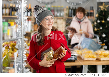 Adolescence girl customer choose consider desserts and sweet snacks, woman in background Adolescence girl customer choose consider desserts and sweet snacks, woman in background 141041383