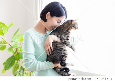 一位女士抱著她的寵物貓。 一位女士抱著她的寵物貓。 141041395