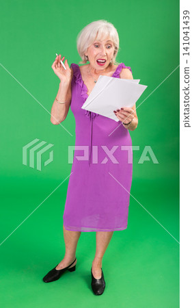 Mature woman in pink dress takes notes in notebook on a green background. Chroma key compositing Mature woman in pink dress takes notes in notebook on a green background. Chroma key compositing 141041439