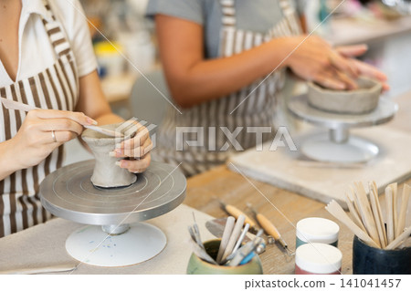 Unrecognizable two young women pottery workshop workers sculpt from raw clay Unrecognizable two young women pottery workshop workers sculpt from raw clay 141041457