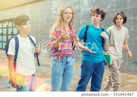 Four teenagers talking about play on walk in street Four teenagers talking about play on walk in street 141041487