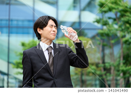 一位商人頂著烈日在戶外喝水。 141041490