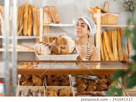 Young woman seller with bread in basket 141041517