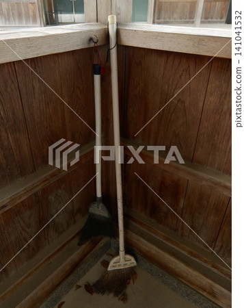 A broom and fallen leaves leaning against the corner of the wooden corridor of the shrine. A broom and fallen leaves leaning against the corner of the wooden corridor of the shrine. 141041532
