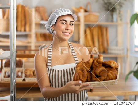 Young woman seller with basket of croissants Young woman seller with basket of croissants 141041707