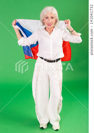Elderly woman in white clothes with large flag of Czech posing on green background. Chroma key compositing Elderly woman in white clothes with large flag of Czech posing on green background. Chroma key compositing 141041732