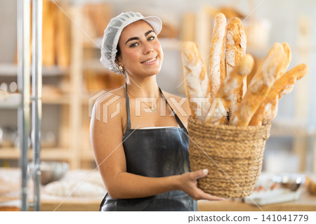 Young female baker with basket of baguettes Young female baker with basket of baguettes 141041779
