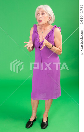 European senior woman in pink dress on green screen background speaks or addresses imaginary partner European senior woman in pink dress on green screen background speaks or addresses imaginary partner 141041782