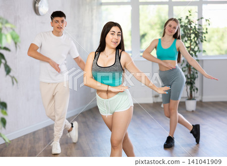 Girl teen perform choreographic exercise and teach energetic house dance with friends Girl teen perform choreographic exercise and teach energetic house dance with friends 141041909