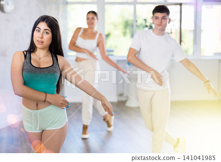 Girl teen perform choreographic exercise and teach energetic house dance with friends Girl teen perform choreographic exercise and teach energetic house dance with friends 141041985