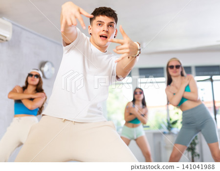 Cheerful teenage guy practicing krumping movements during group class Cheerful teenage guy practicing krumping movements during group class 141041988