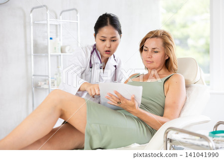 Professional cosmetologist giving documents to patient Professional cosmetologist giving documents to patient 141041990