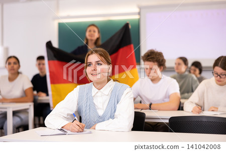 High school teacher holds the flag of Germany in her hands and talks about this country in geography lesson High school teacher holds the flag of Germany in her hands and talks about this country in geography lesson 141042008