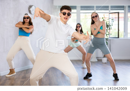 Guy and group of young girls in dark glasses and ball cap dance modern Jazz-modern in fitness club Guy and group of young girls in dark glasses and ball cap dance modern Jazz-modern in fitness club 141042009
