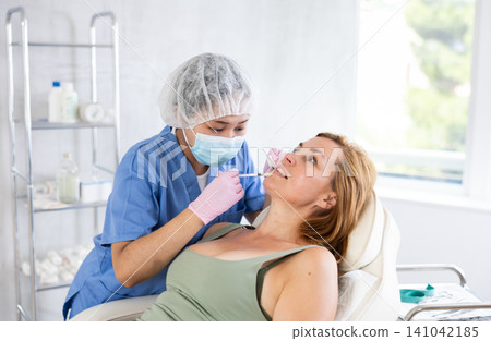 Woman getting procedure of injection contouring and lip augmentation for facial correction in clinic Woman getting procedure of injection contouring and lip augmentation for facial correction in clinic 141042185